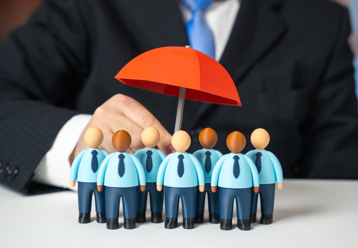Business team standing together under an umbrella representing risk management