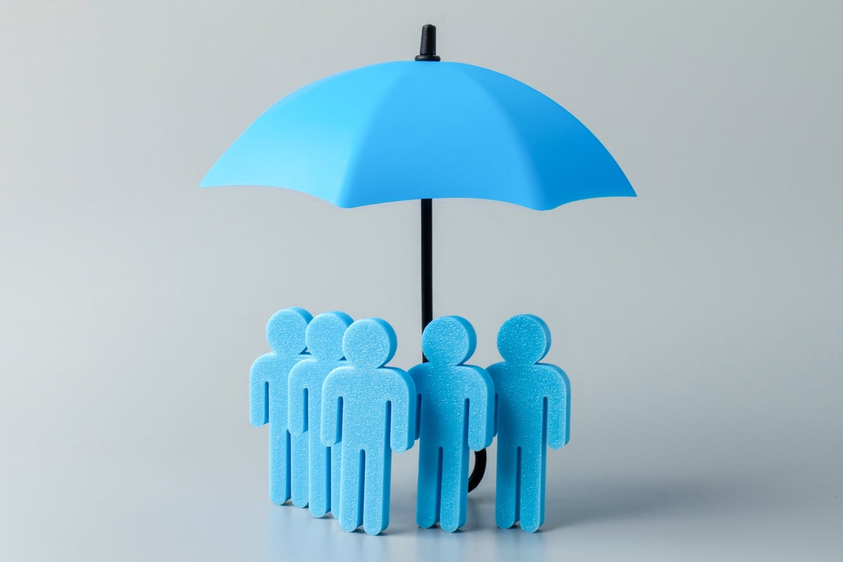 Group of blue figures standing together under a blue umbrella representing collective insurance protection